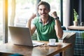 Yes i win! Young happy successful excited businessman in green t-shirt sitting with laptop and celebrating his victory and success Royalty Free Stock Photo