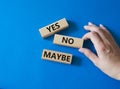 Yes No Maybe symbol. Concept word Yes No Maybe on wooden blocks. Beautiful blue background. Businessman hand. Business and Yes No Royalty Free Stock Photo