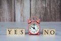Yes No text on wooden block cube with alarm clock set at 10 o'clock. Royalty Free Stock Photo