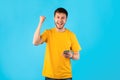 Excited man using mobile phone at studio, celebrating win Royalty Free Stock Photo