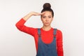 Yes sir! Portrait of strict responsible girl with hair bun in denim overalls giving salute listening to order with serious