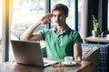 Yes sir! Young businessman in green t-shirt sitting and looking at laptop display on video call with salute gesture and ready to