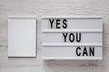`Yes you can` words on a modern board, blank notepad over white wooden background, top view. Overhead, from above. Flat lay Royalty Free Stock Photo