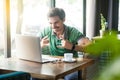 Yes. Young happy excited businessman in green t-shirt sitting, working and looking at laptop screen with rock sign and cheering Royalty Free Stock Photo