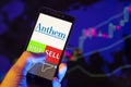 Company logo ANTHEM Inc. on smartphone screen, hand of trader holding mobile phone showing BUY or SELL on background of stock char Royalty Free Stock Photo