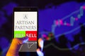 Company logo ARTISAN PARTNERS ASSET MANAGEMENT Inc. on smartphone screen, hand of trader holding mobile phone showing BUY or SELL