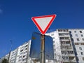 Yield Sign or Give Way against the blue sky and a multi-storey residential building. Road Markings and traffic Rules concept. Tran Royalty Free Stock Photo