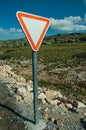 YIELD traffic signpost on roadside and rocky landscape