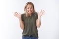 Yikes sorry. Studio shot of awkward cute blond woman raising palms in apology gesture smiling excusing for not making Royalty Free Stock Photo