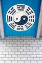 Yin and Yang symbol on a blue background above a brick wall Royalty Free Stock Photo