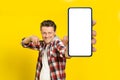 Yo, look at this. Happy handsome man pointing at huge smartphone with white empty screen, wearing red plaid shirt Royalty Free Stock Photo