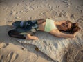 Yoga on the beach. Beautiful woman lying on the sand, practicing Supta Virasana Reclining Hero Pose. Slim body. Healthy spine. Royalty Free Stock Photo