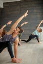 Yoga beginners exercising against grey wall, doing yoga or pilates posture.