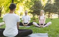 Yoga beginners listening to instructor sitting in Lotus pose