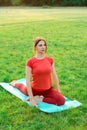 Yoga class in nature. Stretching lessons on green grass in the park. A girl on a yoga mat practices yoga in a pigeon pose.