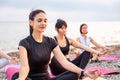 Yoga class at sea coast. Group of Caucasian women meditating on sports mats at pebble beach. Outdoor training and Royalty Free Stock Photo