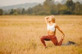 Yoga concept. Young woman dawn performs workout in park, yellow grass field