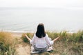Yoga day. Stylish hipster girl sitting on beach in yoga pose and relaxing. Happy boho woman practicing yoga and meditation at sea Royalty Free Stock Photo