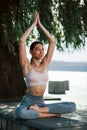 Yoga exersice. Girl in sportive clothes sits outdoors near the tree