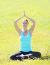 Yoga girl meditates sitting on grass in summer day