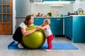 Yoga at home. A smiling young mother leaning on a fit ball and talking with her baby. The concept of fitness with children at home Royalty Free Stock Photo