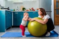 Yoga at home. A young mother leaning on a fit ball, calms her crying baby. The concept of fitness with children at home Royalty Free Stock Photo