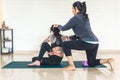 Yoga instructor correcting posture of a student doing ardha matsyendrasana during a class