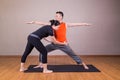 Yoga instructor correcting student performing Warrior 2 or Virabhadrasana 2