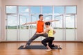 Yoga instructor correcting student performing Warrior 2 or Virabhadrasana 2