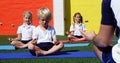 Yoga instructor instructing children in performing yoga