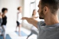 Yoga male trainer giving master class to group of students.