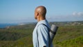 Yoga man looking sea in sunlight. Athletic guy holding mat contemplating coast