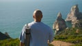 Yoga man walking edge cliff holding mat. Focused sportsman looking ocean coast