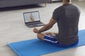 Yoga meditation course online. A man meditates using a laptop video training sitting on the floor at home. Royalty Free Stock Photo