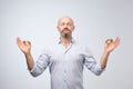 Handsome bald man with bristle keeping eyes closed while meditating, feeling relaxed, calm, peaceful