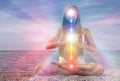 Yoga meditation outdoors. Glowing seven all chakra. Woman sits in a Upward Salute pose on beach sunset view, Kundalini energy.