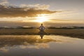 Yoga meditation silhouette lotus sunrise beach, water reflection of man in yoga pose, mindfulness wellbeing concept Royalty Free Stock Photo