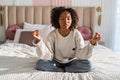 Yoga mindfulness meditation. Young healthy African girl practicing yoga at home. Woman sitting in lotus pose on bed