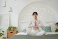 Yoga mindfulness meditation. Young healthy woman practicing yoga in bedroom at home. Woman sitting in lotus pose on bed Royalty Free Stock Photo
