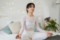 Yoga mindfulness meditation. Young healthy woman practicing yoga in bedroom at home. Woman sitting in lotus pose on bed Royalty Free Stock Photo