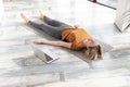 Yoga nidra practice online at home. Caucasian adult woman lying on the floor in shavasana indoor, next to her laptop