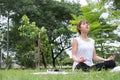 Yoga outdoors in public park. Asian woman sits in lotus position Royalty Free Stock Photo