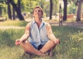 Beautiful mature woman meditating in green park