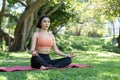 Yoga at park. Young asian woman in lotus pose sitting on green grass. Concept of calm and meditation. Royalty Free Stock Photo
