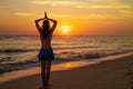 Yoga pose. Woman standing on the beach, practicing yoga. Young woman raising arms with namaste mudra during sunset golden hour.