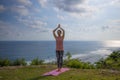 Yoga pose. Woman practicing yoga. Young woman raising arms with namaste mudra. Outdoor yoga on the cliff. Bali