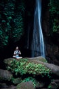 Young Caucasian woman meditating, practicing yoga at waterfall. Hands in namaste mudra. Leke Leke waterfall, Bali, Indonesia Royalty Free Stock Photo