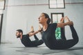 Yoga Practice Exercise Class Concept. Two beautiful people doing exercises.Young woman and man practicing yoga indoors.