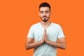 Yoga practice for mind balance. Portrait of peaceful handsome brunette man meditating. indoor studio shot isolated on orange