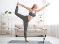 Yoga practice and online home lessons on quarantine. Woman doing exercise, stands on mat with laptop Royalty Free Stock Photo